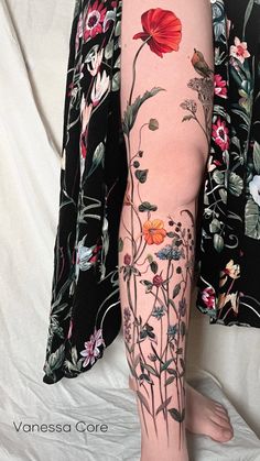 a woman's leg with flowers and leaves on it