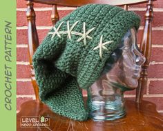 a crocheted green hat with white stars on it sitting on top of a wooden chair