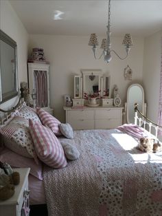 a bed room with a neatly made bed next to a dresser and mirror on the wall