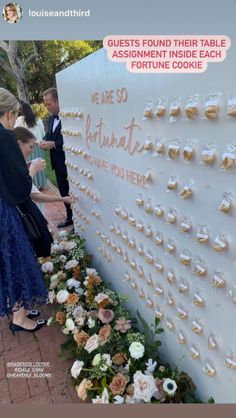 people standing around a wall with flowers on it