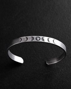 This exquisite silver bracelet, named "MOON PHASE," embodies the mystery and rhythmic beauty of nature. Reflecting the various phases of the Moon, it symbolizes cyclicality, rebirth, and the ever-changing nature of life. Each lunar phase on the bracelet carries its own unique significance, from the new moon representing fresh beginnings to the full moon embodying fulfillment.  A reminder of the importance of intuition and understanding one's inner rhythm, this bracelet is a symbol of harmony and Silver Moon Shaped Adjustable Bracelet, Adjustable Silver Moon Bracelet, Adjustable Silver Moon-shaped Bracelets, Adjustable Silver Moon Bracelets, Silver Moon-shaped Sterling Silver Bracelet, Silver Minimalist Moon Bracelet, Silver Symbolic Metal Cuff Bracelet, Mens Silver Cuff Bracelet, Silver Arm Cuff