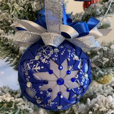 a blue ornament hanging from a christmas tree with snowflakes on it