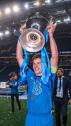 a man holding up a trophy on top of a field