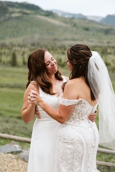 two women in wedding dresses hugging each other