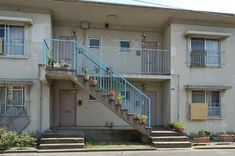 an apartment building with stairs leading up to the front door and flowers on the balconies