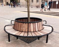 a wooden bench sitting on the side of a street next to a tree and stairs