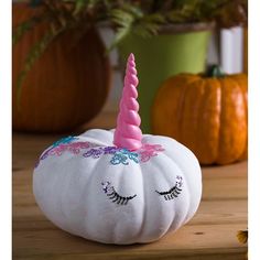 a white pumpkin with a pink unicorn horn on it