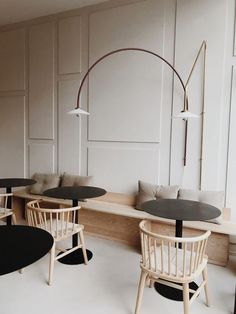 an empty restaurant with round tables and chairs in the center, along with white walls