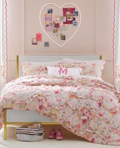 a bedroom with pink walls and white bedding has a heart shaped mirror above the bed