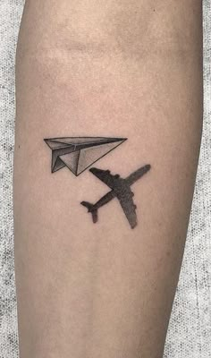 an airplane and a paper plane tattoo on the left calf leg, with black ink