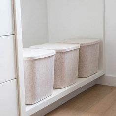 two white bins sitting on top of a shelf next to each other in a room