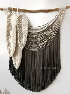 a white wall hanging with black fringes and two large feathers on it's side