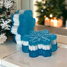 two blue and white candles sitting on top of a counter next to a christmas tree