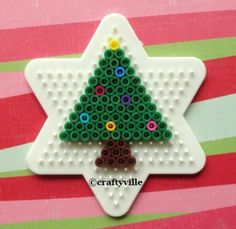 a christmas tree ornament made out of legos on a pink and green striped background