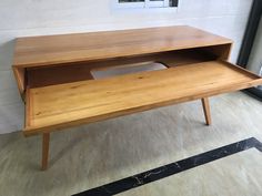 a wooden desk sitting on top of a hard wood floor next to an open window