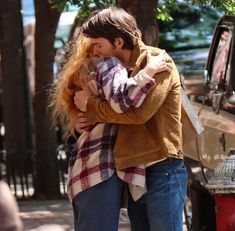 a man and woman embracing each other on the sidewalk next to a fire hydrant