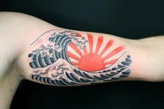 a man's arm with a wave tattoo on it and the sun in the background