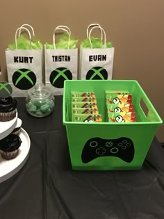 a table with cupcakes, candy and bags on it that are decorated like video game controllers