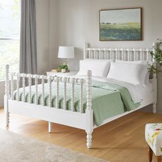 a white bed sitting in a bedroom on top of a hard wood floor next to a window