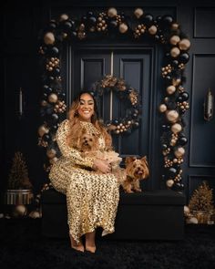 a woman sitting on a bench with her dog in front of a christmas wreath and door