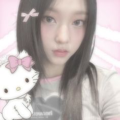 a girl with long black hair and a pink bow on her head is holding a hello kitty doll