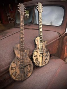 two wooden guitars are sitting on the hood of an old pickup truck with roman numerals