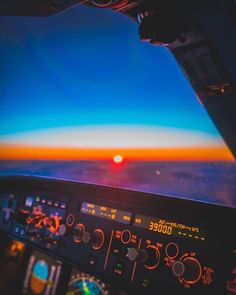 an airplane cockpit with the sun setting in the distance