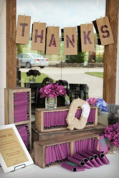 a table with purple flowers and decorations in front of a sign that says thanks, thanks