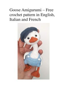 a small crocheted duck wearing a blue and white hat is held in someone's hand