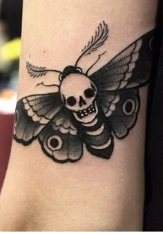 a black and white tattoo with a butterfly on it's arm that has a skull in the middle