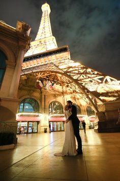 a bride and groom standing in front of the eiffel tower