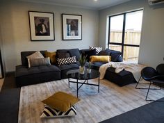 a living room with black couches and yellow pillows on the rugs in front of large windows