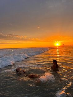 two people swimming in the ocean at sunset