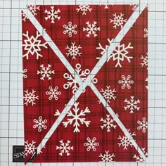 a red and white quilt with snowflakes on the top, next to a ruler