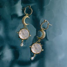 Step into a dreamscape of enchantment with our Lover's Eyes Earrings, where reality and fantasy dance in a celestial waltz. Crafted from 18k gold-plated 925 sterling silver, these earrings are intricately engraved and the Lovers Eye Shell Pendant, suspended delicately from a crescent moon, creates an otherworldly tableau. Within the 2cm diameter pendant, a mesmerizing eye peers out, framed by a star.As the eyes and stars dangle gracefully, each movement sends ripples through the fabric of this s Celestial Metal Jewelry, Celestial Teardrop Pierced Jewelry, Ethereal Handmade Dangle Jewelry, Handmade Ethereal Dangle Jewelry, Celestial Gold-plated Single Earring, Celestial Single Gold Plated Earring, Celestial Gold Plated Single Earring, Celestial Brass Jewelry For Anniversary, Ethereal Jewelry For Anniversary With Moon Phase