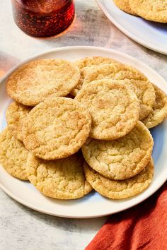 several cookies on a white plate next to a glass of tea