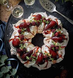 a cake with strawberries and whipped cream is on a black plate next to silverware