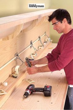 a man is working on some wood work with drillers and screwdrivers in his hand