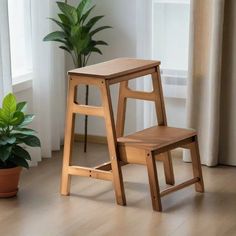 two wooden stools sitting next to each other in front of a potted plant