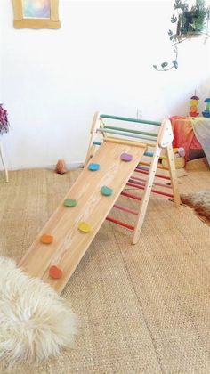 a child's wooden slide with colorful rocks on it in the corner of a room