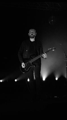 a man standing in front of a guitar on stage