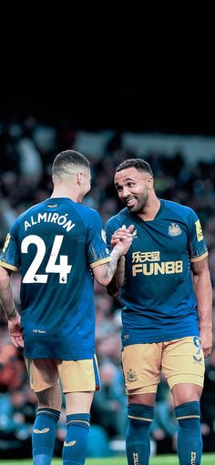 two soccer players standing next to each other on a field