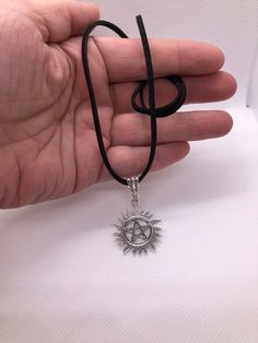 Supernatural Anti Possession Suede Cord Necklace. Made with genuine suede cord, a silver charm holder, you can choose any of ones shown in the display photos, if one isn't selected, you'll receive one that's chosen at random and a silver pentagram charm that looks like Dean and Sam's tattoos on the show and is very detailed. These suede necklaces come in a variety of colors, black, red, brown, dark brown, the dark brown is really dark and looks almost like black n the photos, light brown, beige, gray and white suede. Red and white suede is beautiful and really stands out when worn. All colors of suede look amazing with this charm and are shown in the photos. The one shown first is the black one and is 18 inches long and is adjustable. Please include the color and size you would like to hav