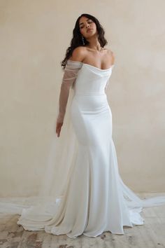 a woman in a white wedding dress posing for the camera with her hands on her hips