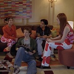 four people sitting on a couch in a living room with one person holding a wii controller