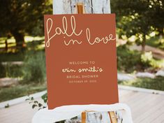 an easel with a sign that says fall in love and welcomes the bride