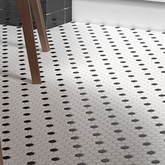 a bathroom with black and white tiles on the floor next to a wooden stand in the corner