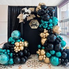 balloons are arranged in the shape of an arch with black, gold and teal colors