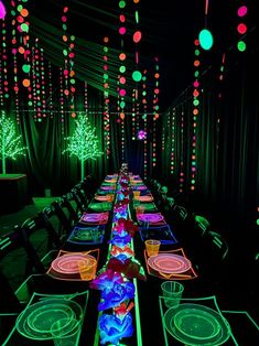 a long table is lit up with colorful lights and plates on the tables in front of them