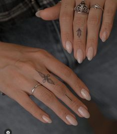 two hands with tattoos on their fingers and one has a butterfly tattoo on the middle finger